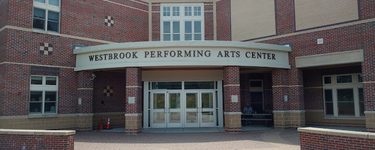 The exterior of the westbrook performing arts center. two sets of glass double doors are set into a large brick school building.